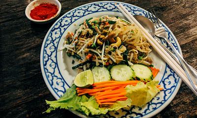 What are some must-try Thai dishes while visiting Thailand?
